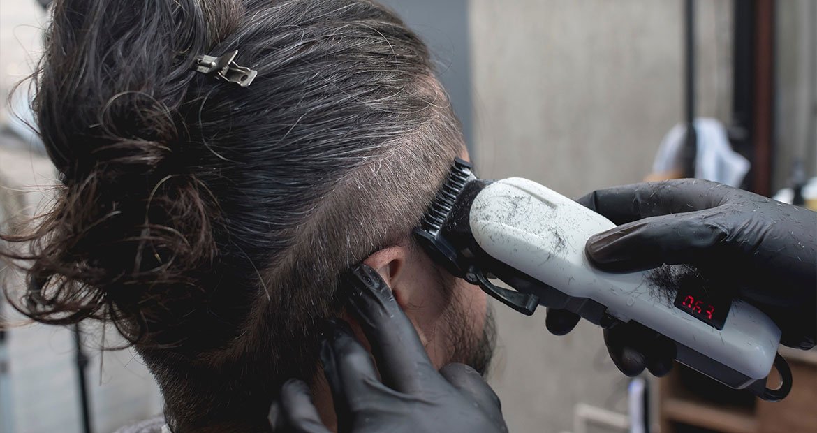 Barbeiro realiza corte degradê em cabelo longo masculino de cliente